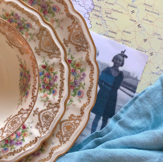 Story of a Teacup event image: Teacup, saucer, and plate with floral and gold motif next to an old photo of a girl and a map